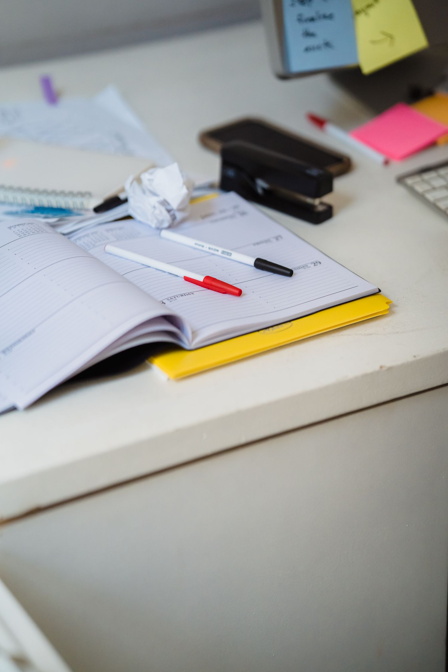 A planner, pens and office supplies on a desk
